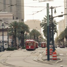 a red trolley car traveling down a street next to tall buildings