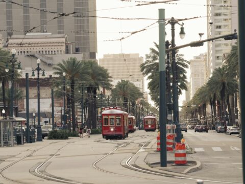 a red trolley car traveling down a street next to tall buildings