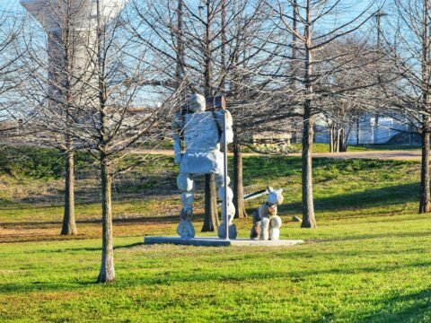 A statue of a man and a dog in a park